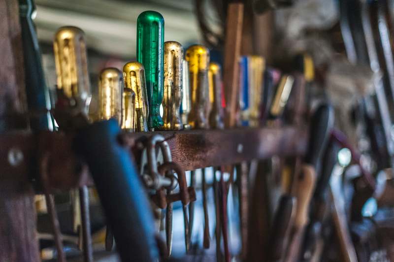 Close-up of professional-grade screwdrivers arranged neatly on a well-lit workshop bench with wood grain background