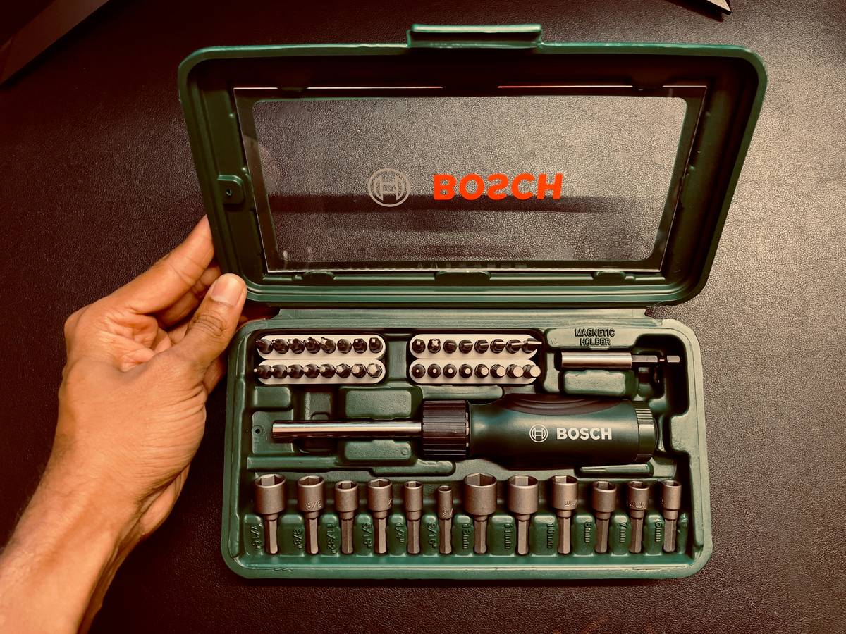 phone repair tool screwdriver shown next to iPhone 14 logic board and pentalobe screws on a anti-static mat